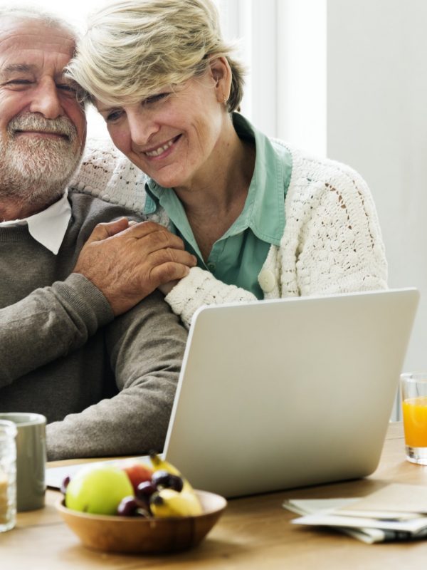 Senior couple hugging while using a laptop